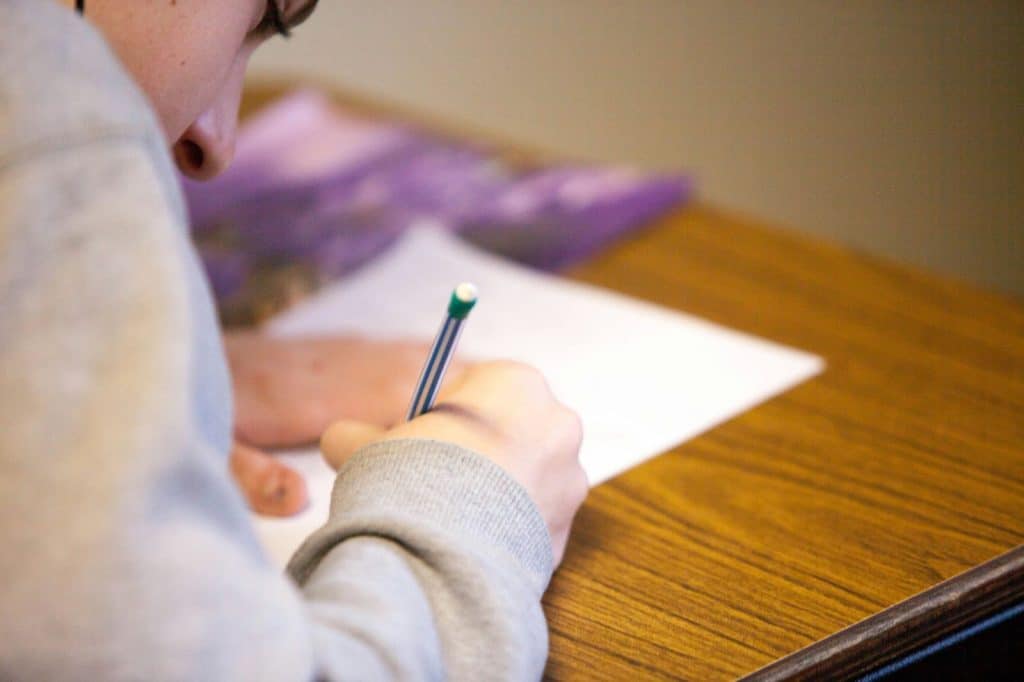 student filling up a sheet of paper - featured image